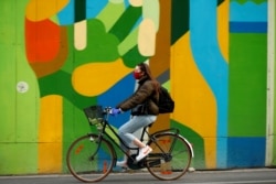 FILE PHOTO: A woman wearing a protective mask rides her bicycle during the coronavirus disease (COVID-19) outbreak, in Brussels, Belgium April 16, 2020. REUTERS/Francois Lenoir/File Photo