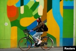 FILE PHOTO: A woman wearing a protective mask rides her bicycle during the coronavirus disease (COVID-19) outbreak, in Brussels, Belgium April 16, 2020. REUTERS/Francois Lenoir/File Photo