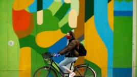 FILE PHOTO: A woman wearing a protective mask rides her bicycle during the coronavirus disease (COVID-19) outbreak, in Brussels, Belgium April 16, 2020. REUTERS/Francois Lenoir/File Photo