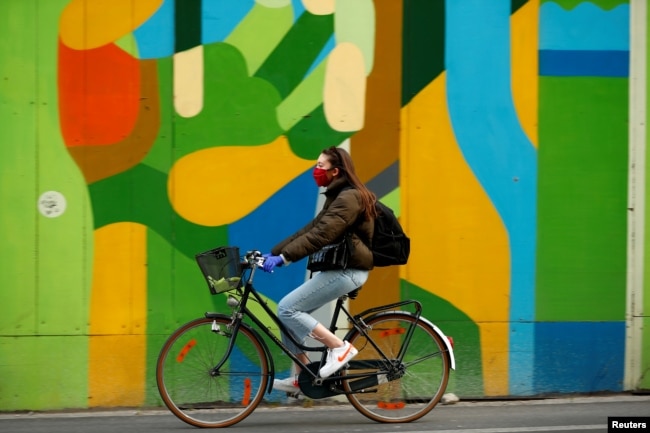 FILE PHOTO: A woman wearing a protective mask rides her bicycle during the coronavirus disease (COVID-19) outbreak, in Brussels, Belgium April 16, 2020. REUTERS/Francois Lenoir/File Photo
