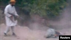 This still image taken from undated video footage depicts a man Afghan officials identified as a member of the Taliban firing his rifle at a woman accused of adultery during her execution in a village outside Kabul, Afghanistan.