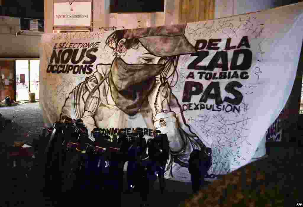 Police break up a protest camp at the Tolbiac campus, part of the Sorbonne University, in front of a banner reading 'They select, we occupy. The ZAD (the "Zone to defend") in Tolbiac, no expulsion,' in Paris.