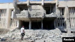 FILE - A man inspects damage at the entrance of the National Hospital of al-Tabqa, caused by what activists said was an airstrike by forces of Syria's President Bashar Al-Assad on the hospital, beside al-Tabqa military base, west of Raqqa, Aug. 23, 2014. 