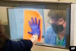 FILE - Andrew Hougardy, a worker at the King County election headquarters in Renton, Washington, views an "alternative format" ballot held up by a co-worker during ballot processing and counting, Oct. 23, 2020.