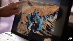 FILE _ Sirwan Jalal, Director of Mass Graves for the Kurdish Regional Government, points to an image of the site of a mass grave during an interview with the Associated Press in Irbil, northern Iraq. 