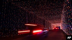 Passenger vehicles move through a tunnel of holiday lights at a display set up at the Cumberland Fair Grounds, Tuesday, Dec. 14, 2021, in Cumberland, Maine. (AP Photo/Robert F. Bukaty)
