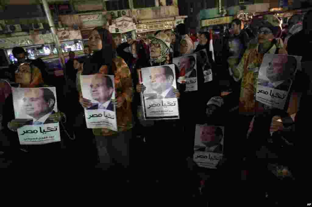 Supporters of former army chief Abdel-Fattah el-Sissi hold posters of him with Arabic writing that reads &quot;Long Live Egypt&quot; while watching his first televised interview on a big screen, Cairo, May 5, 2014.