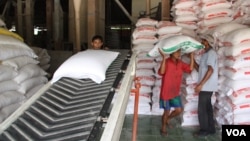 Workers carry bags of rice off a conveyor belt to stak in trucks, Tien Giang, Vietnam, September 14, 2012. (D. Schearf/VOA)