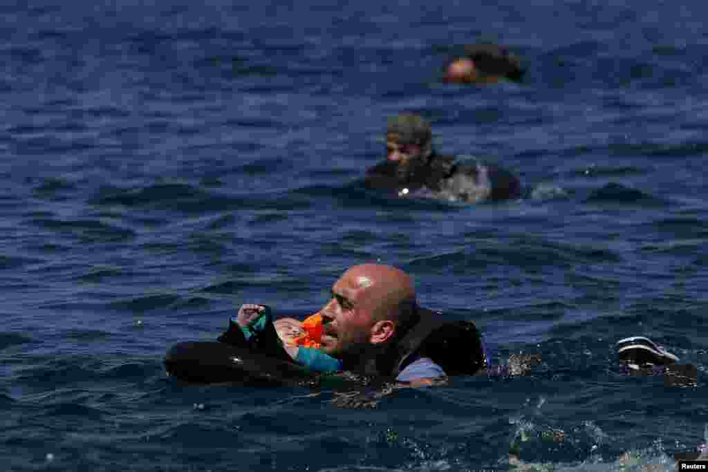 A Syrian refugee holding a baby in a lifetube swims towards the shore after their dinghy deflated some 100m away before reaching the Greek island of Lesbos, Sept. 13, 2015. Of the record total of 432,761 refugees and migrants making the perilous journey across the Mediterranean to Europe so far this year, an estimated 309,000 people had arrived by sea in Greece, the International Organization for Migration (IMO) said. About half of those crossing the Mediterranean are Syrians fleeing civil war, according to the United Nations refugee agency.