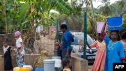 FILE — People queue at a public tap after its reopens in Kaweni district in Mamoudzou on the French Indian Ocean island of Mayotte on October 14, 2023.