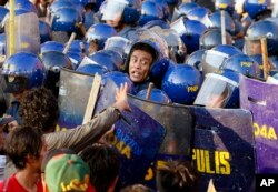 A police officer yells at his colleagues during a clash with protesters when the latter tried to force their way closer to the gates of the US Embassy in Manila to mark the International Labor Day, May 1, 2016 in Manila, Philippines.