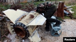 Một chiến binh phe nổi dậy, Quân đội Syria Tự do, ở Latakia, quan sát một vỏ đạn chưa nổ