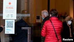 People pass by a sign spelling out COVID-19 rules at the entrance to the Dresden State Art Collections, in Dresden, Germany, Nov. 19, 2021.