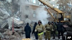 This photo provided by the Russian Emergency Situations Ministry taken from TV footage shows Emergency Situations employees working at the scene of a collapsed section of an apartment building, in Magnitigorsk, Russia, Dec. 31, 2018.