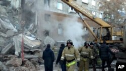This photo provided by the Russian Emergency Situations Ministry taken from TV footage shows Emergency Situations employees working at the scene of a collapsed section of an apartment building, in Magnitigorsk, Russia, Dec. 31, 2018.
