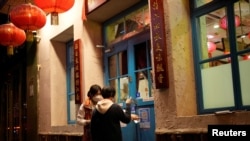 A waiter guides a customer to scan a health QR code outside a restaurant as coronavirus disease (COVID-19) outbreaks continue in Shanghai, China on December 8, 2022. (REUTERS/Aly Song)