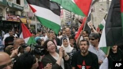 Palestinians wave flags and chant during a rally celebrating the planned signing of a reconciliation agreement between Fatah and Hamas, in the West Bank city of Ramallah, May 4, 2011