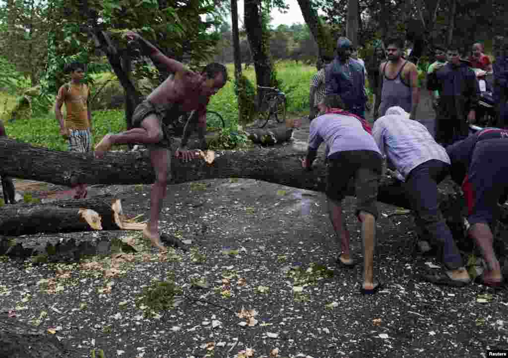 Men try to remove fallen trees from a road due to the rain and wind in the eastern Indian state of Odisha.