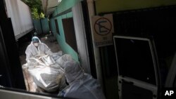 ARCHIVO - Forenses trasladan un cuerpo en la morgue de Tegucigalpa en Honduras, el 21 de junio de 2023.