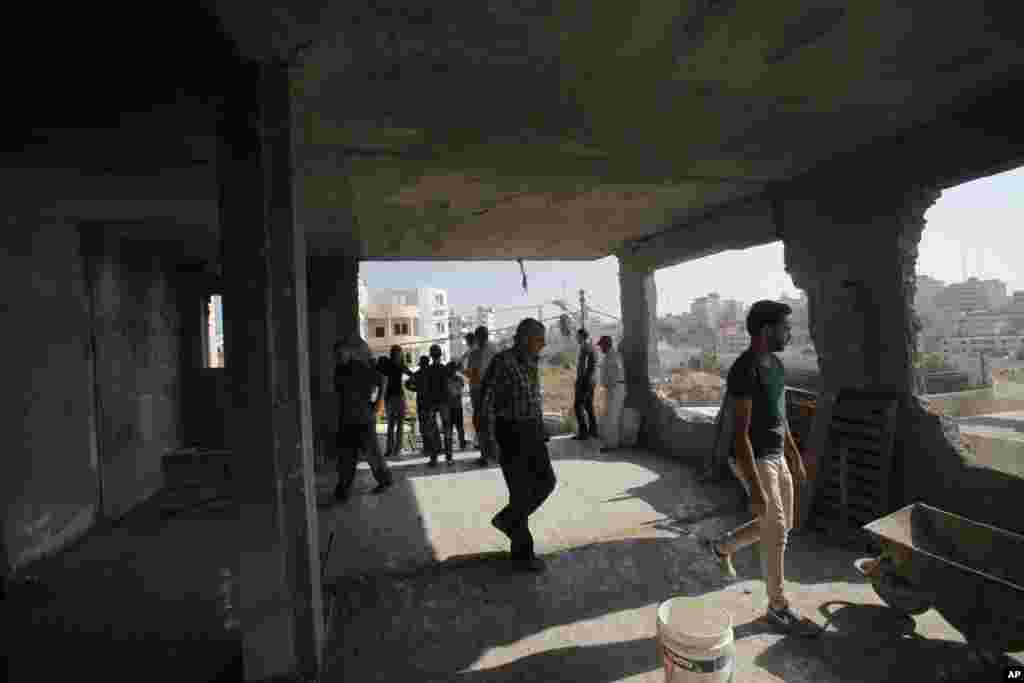 Palestinians inspect the remains of the house of Amer Abu Aisheh, in the West Bank city of Hebron, Aug. 18, 2014. 