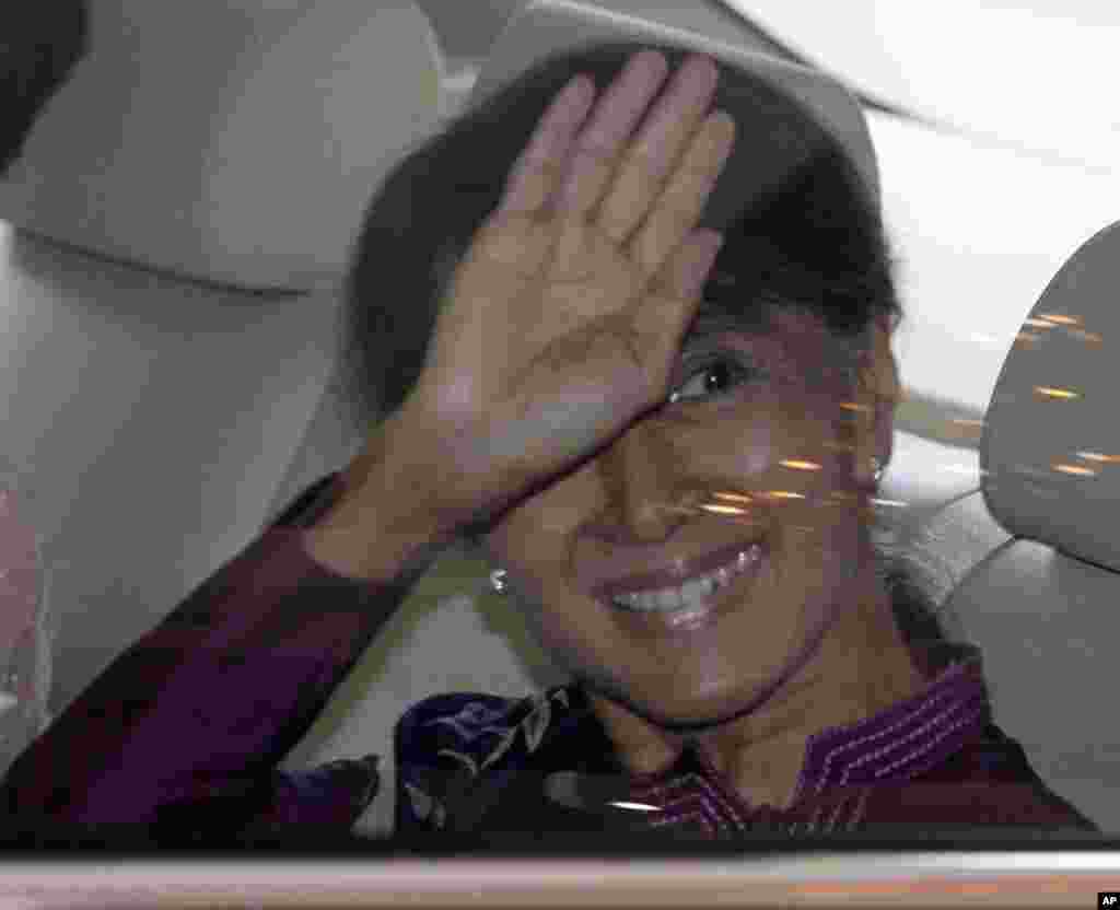 Burma's pro-democracy leader Aung San Suu Kyi waves to photographers as she leaves a hotel in Bangkok, Thailand, May 31, 2012.<br />
