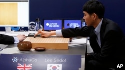 South Korean professional Go player Lee Sedol, right, puts the first stone against Google's artificial intelligence program, AlphaGo, during the Google DeepMind Challenge Match in Seoul, South Korea, March 9, 2016. 