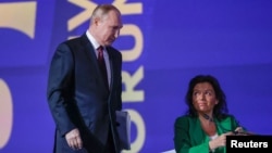 FILE - Russian President Vladimir Putin and RT editor-in-chief Margarita Simonyan are seen on the podium of the St. Petersburg International Economic Forum, in Saint Petersburg, Russia, June 17, 2022.