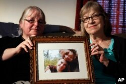 FILE- Linda Boyle, left, and Lyn Coleman hold a photo of their married children, Joshua Boyle and Caitlan Coleman, June 4, 2104, who were kidnapped by the Taliban in late 2012.