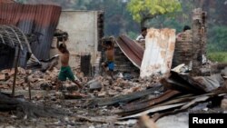 Children recycle goods from the ruins of a market which was set on fire at a Rohingya village outside Maugndaw in Rakhine state, Myanmar, Oct. 27, 2016. 