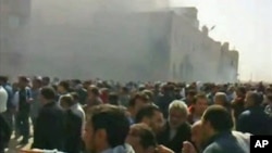 A crowd gathers as smoke billows from a building purported to be the internal security headquarters in Libya's second city of Benghazi in this video still grab, February 20, 2011