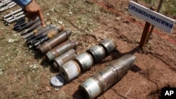 FILE - A Cambodian demining expert points to unexploded bombs displayed on the ground before a destruction ceremony organized by the Cambodia Mine Action Center (CMAC) at the complex of the Preah Vihear temple in Preah Vihear province.