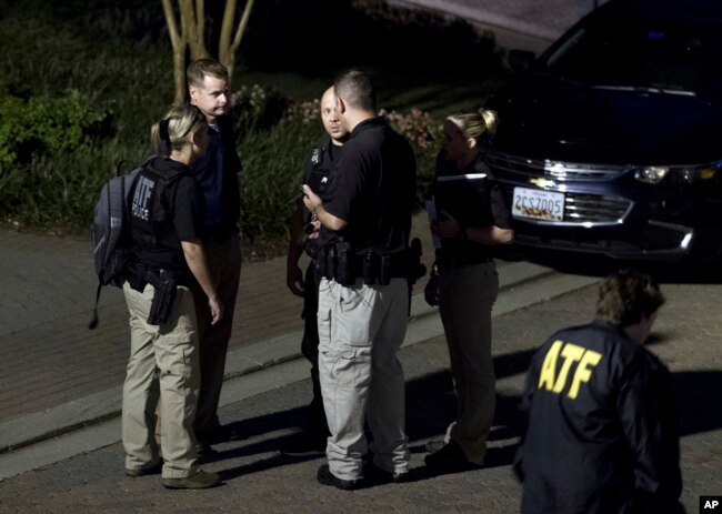 Agentes de la Oficina de Alcohol, Tabaco, Armas de Fuego y Explosivos salen de la casa en Baltimore, Maryland, del sospechoso del tirotoe en Jakcsonville, Florida, el domingo, 26 de agosto de 2018.