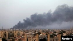 Plumes of black smoke can be seen after clashes between the Benghazi Revolutionaries Shura Council and fighters of renegade general Khalifa Haftar, as they each attempt to seize control of the airport from the council in Benghazi, Libya, Aug. 23, 2014.