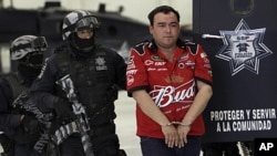 Gilberto Barragan Balderas, right, is escorted by police officers as he is presented to the media in Mexico City, Friday, May 20, 2011