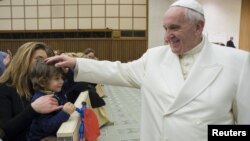 Pope Francis blesses a child during a special audience with Vatican employees for Christmas greetings at the Paul VI hall at the Vatican, Dec. 21, 2015.