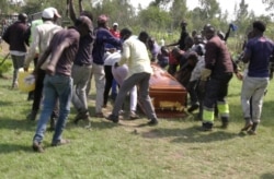 FILE - Mourners and fans of Kenyan musician Bernard Obonyo, whose stage name is Abenny Jachiga, carry his coffin away as they proceed his burial under the rules for the suspected COVID-19 cases, at Chiga village near Kisumu, Kenya, June 12, 2020.
