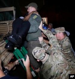 National Guard members help brace a rescuer as he lowers a resident from a rescue vehicle, Aug. 28, 2017 in Lake Charles, La., after flooding from Tropical Storm Harvey's almost constant rain over the last two days overcame the city's drainage system.