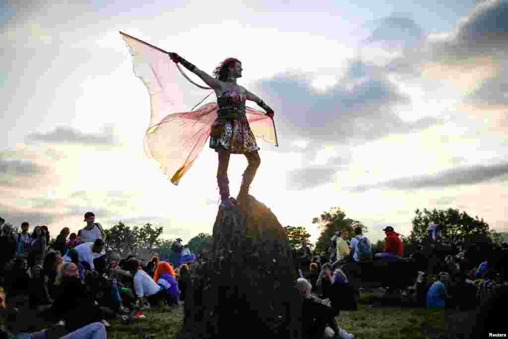 A person dances during sunset at the stone circle during Glastonbury Festival at Worthy farm in Somerset, Britain, June 26, 2019.