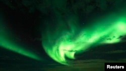 FILE - A tourist takes photos of an Aurora Borealis (Northern Lights) over the Bals-Fiord north of the Arctic Circle. Northern latitudes may see an aurora because of sunspot activity.