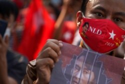 Manifestante sostiene sostiene una foto de la líder Aung San Suu Kyi frente a la embajada de Birmania, el 1 de febrero de 2021.