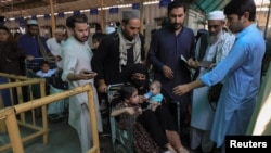 People get their papers checked by the officer while they cross main Afghanistan-Pakistan land border crossing, in Torkham, Pakistan, Sept. 15, 2023.