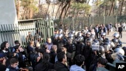 In this photo taken by an individual not employed by the Associated Press and obtained by the AP outside Iran, anti-riot Iranian police prevent university students to join other protesters over Iran weak economy, in Tehran, Iran, Saturday, Dec. 30, 2017.