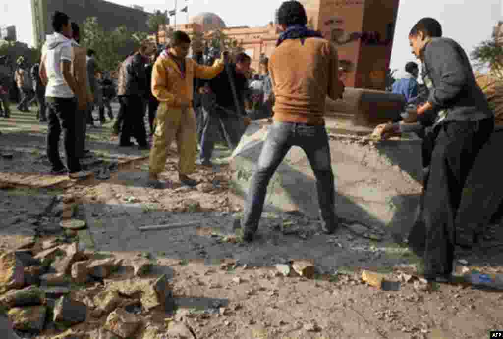 Anti-government protesters destroy a monument in order to use the rubble for rocks during clashes in Tahrir, or Liberation square, in Cairo, Egypt, Wednesday, Feb. 2, 2011. Several thousand supporters of President Hosni Mubarak, including some riding hors