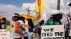 Dos niñas sostienen carteles mientras latinos en Florida, junto con personas negras, indígenas y otros aliados, protestan contra el proyecto de ley SB 1718, en Immokalee, Florida el 1 de junio de 2023.