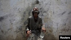 A man cools off from a public tap after filling bottles during intense hot weather in Karachi, Pakistan, June 23, 2015.