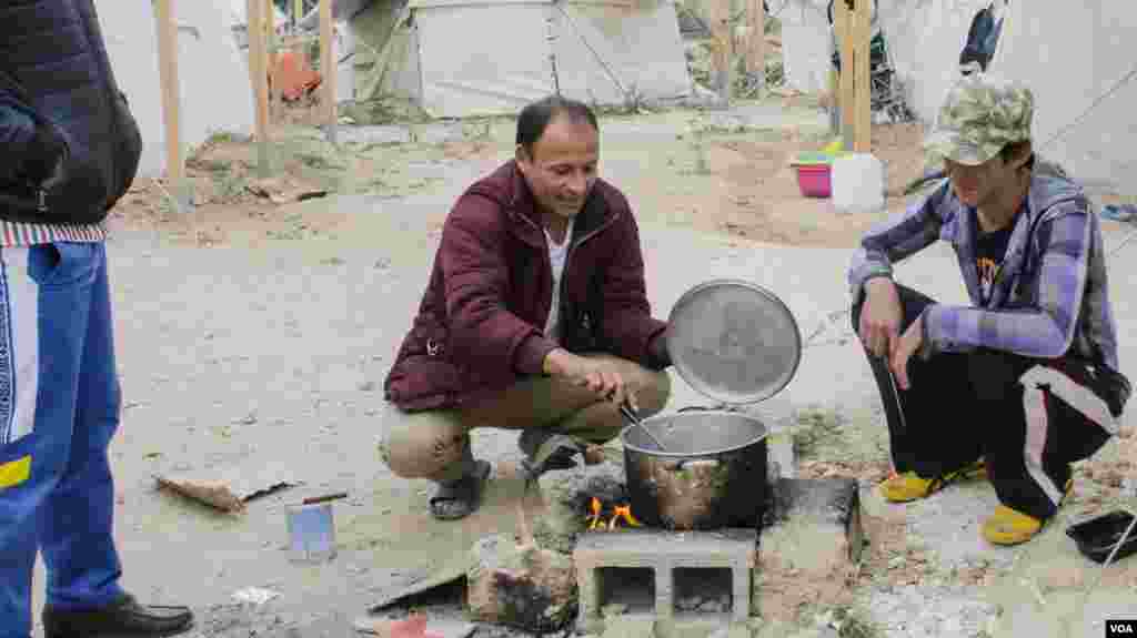 A meal is prepared in Schisto camp. In northern Greece, thousands of refugees live in tents in warehouses, prompting space fears over increasing use of fires over the winter in a confined space. (J. Owens for VOA)