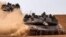 Israeli army battle tanks move near the border with the Gaza Strip at a location in southern Israel on May 13, 2024, amid the ongoing conflict in the Palestinian territory between Israel and the Hamas movement. 