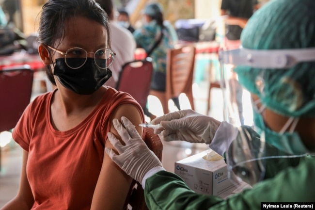 Seorang perempuan menerima satu dosis vaksin AstraZeneca COVID-19 saat program vaksinasi massal untuk Kawasan Wisata Hijau di Sanur, Bali, 23 Maret 2021. (Foto: REUTERS/Nyimas Laula)