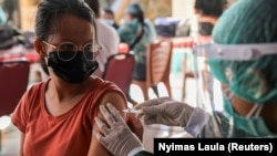 Seorang perempuan menerima satu dosis vaksin AstraZeneca COVID-19 saat program vaksinasi massal untuk Kawasan Wisata Hijau di Sanur, Bali, 23 Maret 2021. (Foto: REUTERS/Nyimas Laula)