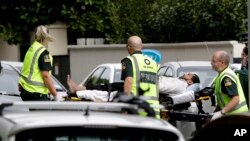 Ambulance staff take a man from outside a mosque in central Christchurch, New Zealand, March 15, 2019. A witness says many people have been killed in a mass shooting at a mosque in the New Zealand city of Christchurch.
